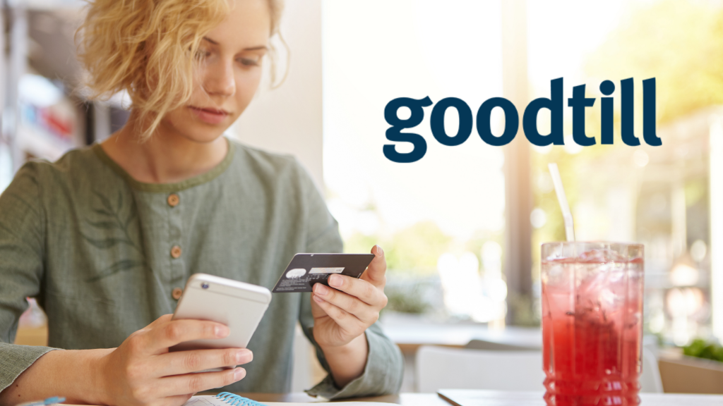 woman paying with her phone in a restaurant with a cold beverage in front of her