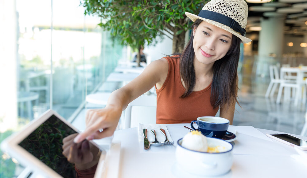 Woman,Ordering,Food,On,Tablet,Computer,In,Restaurant